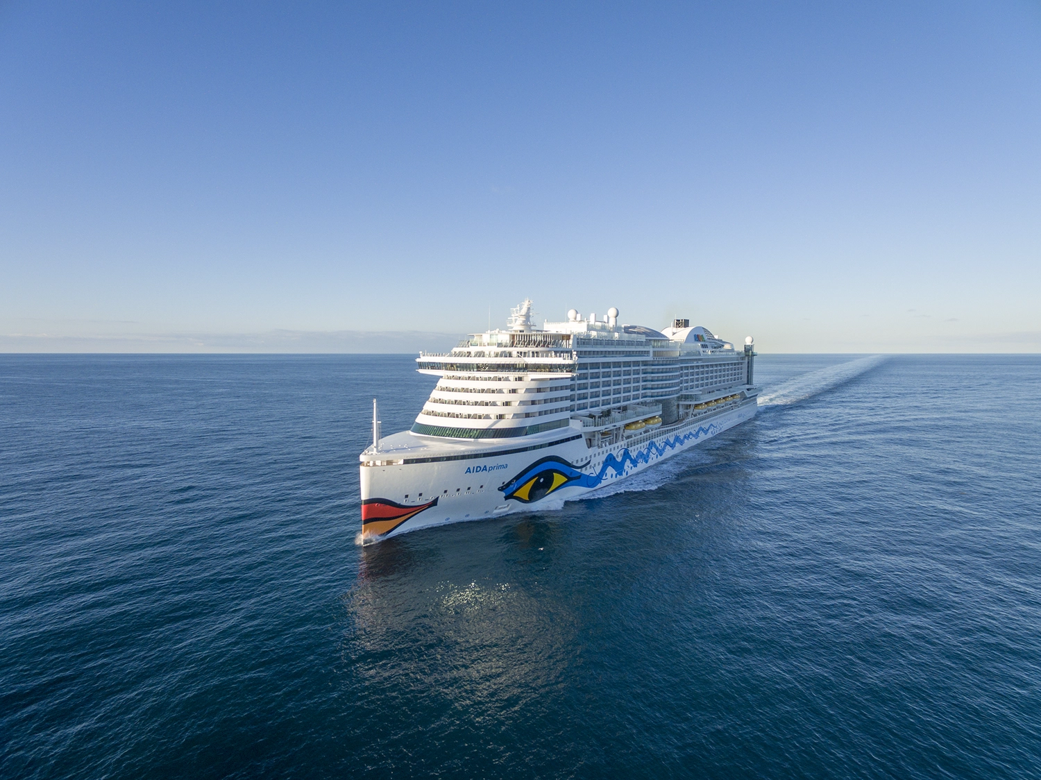 GTS - Reiseservice - Luftaufnahme eines großen weißen Kreuzfahrtschiffs, das durch ruhiges, tiefblaues Wasser fährt.