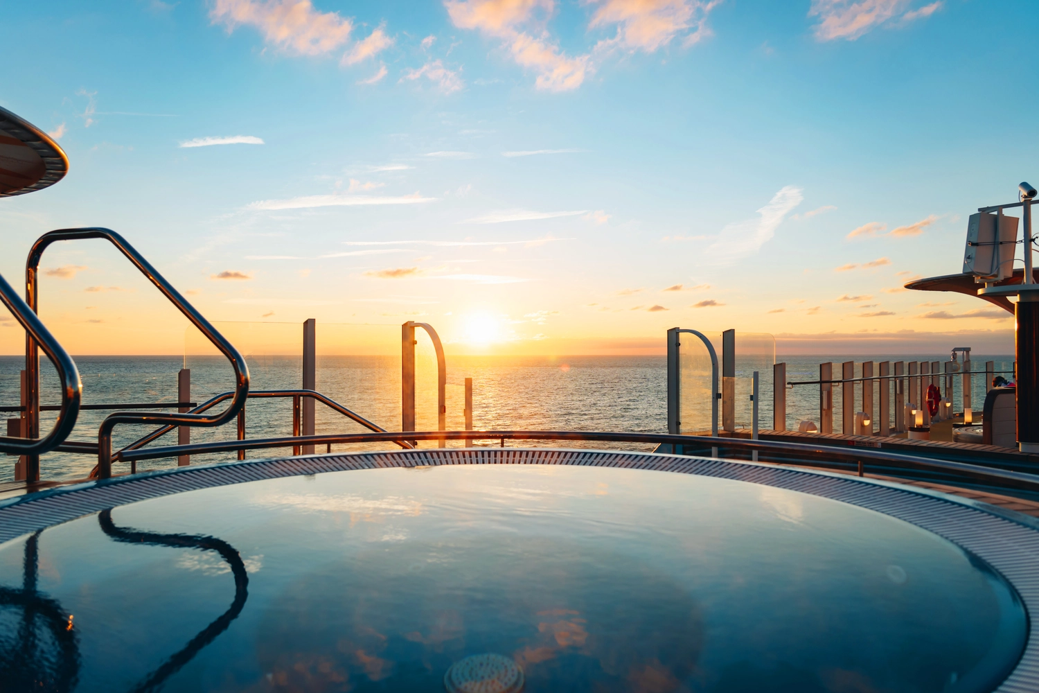 GTS - Reiseservice - Ein luxuriöser Whirlpool auf dem Deck eines Kreuzfahrtschiffs mit Blick auf einen atemberaubenden Sonnenuntergang über dem Meer.