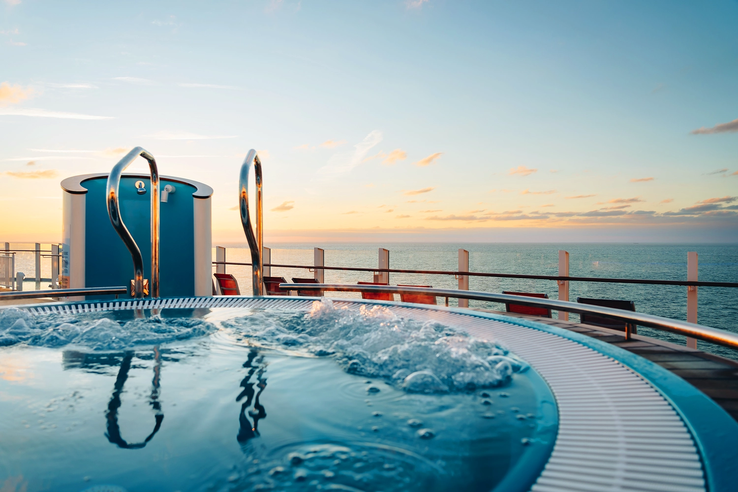 GTS - Reiseservice - Ein sprudelnder Whirlpool auf dem Schiffsdeck in der Abenddämmerung mit Blick auf das offene Meer.