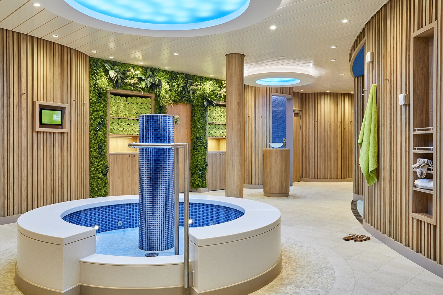 GTS - Reiseservice - Moderner Wellnessbereich auf einem Kreuzfahrtschiff mit Holzvertäfelung, einem runden Fußbad und begrünten Wänden.
