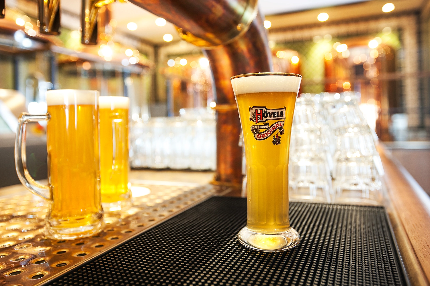 GTS - Reiseservice - Gläser mit Fassbier stehen an einer Bar neben einem Kupferzapfhahn.